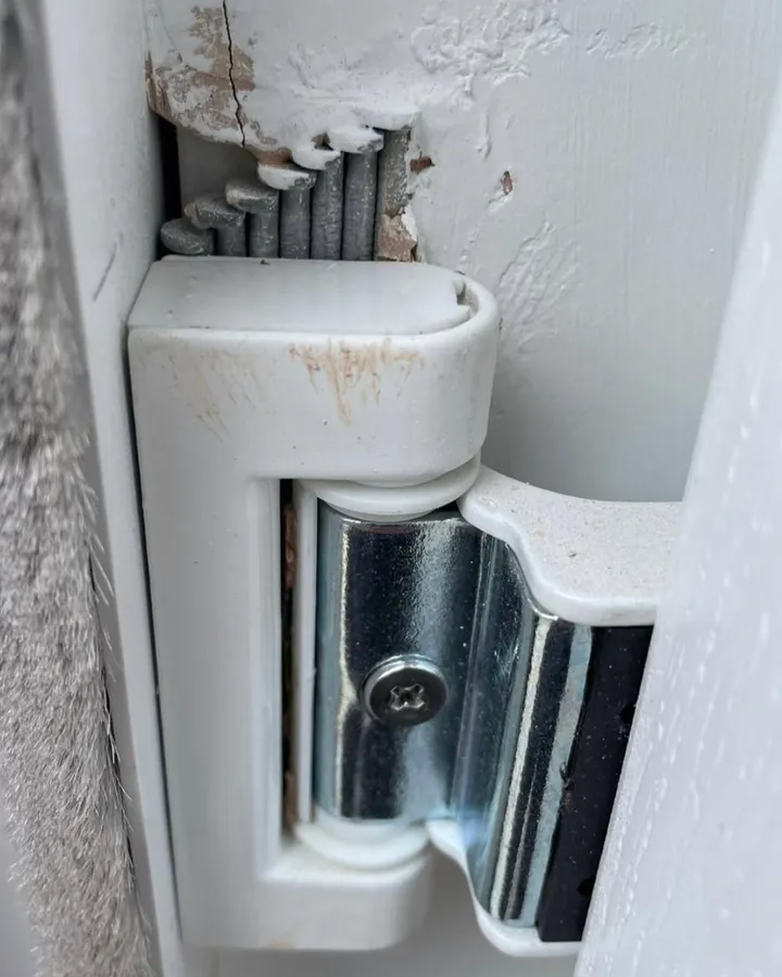 A white uPVC door hinge with a chrome pin, seen close up.